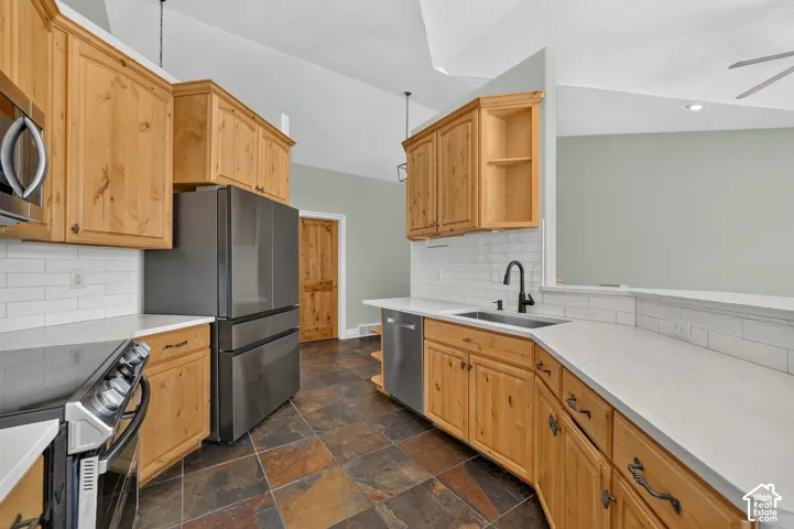 Kitchen featuring light wood cabinetry, white subway tile backsplash, white countertops, and stainless steel appliances
