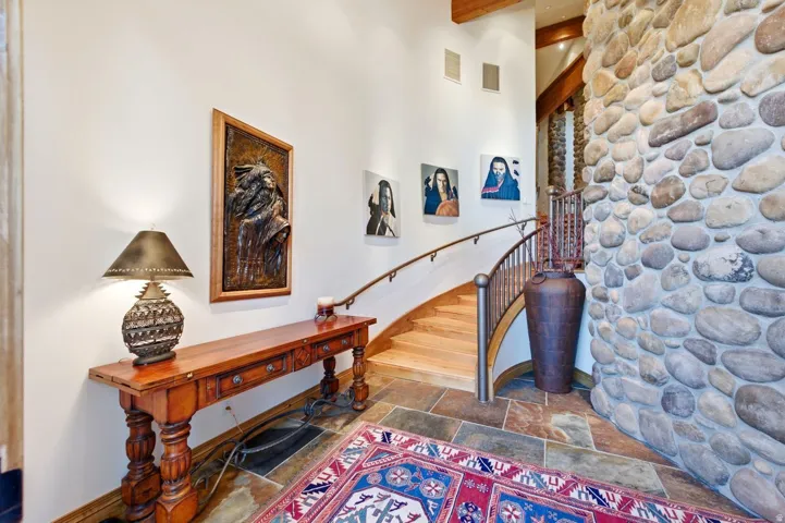 Entryway featuring a stone accent wall, natural wood staircase with a metal railing, and slate tile flooring