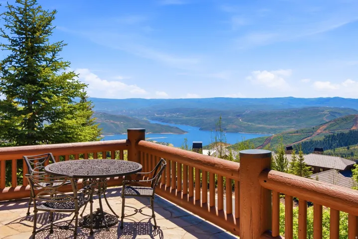 Stone patio with a log railing overlooking a large lake and distant mountains