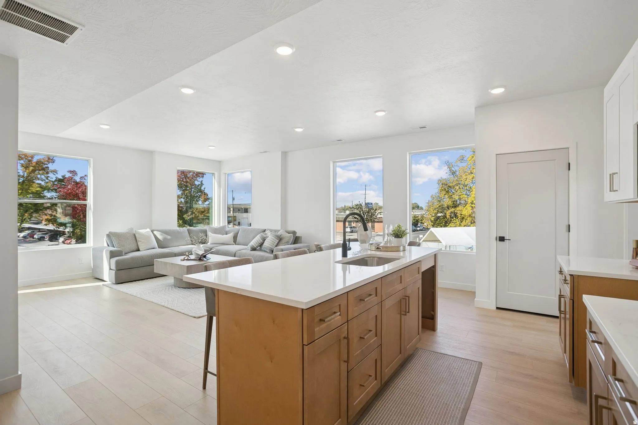 Open-concept living space featuring wood-finish flooring, recessed lighting, and multiple large windows