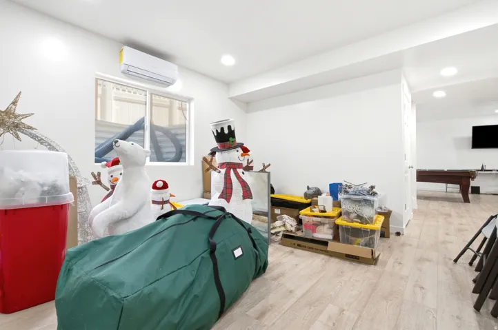 Interior space featuring light wood-finish flooring, recessed lighting, a wall-mounted air conditioning unit, and a window with blinds
