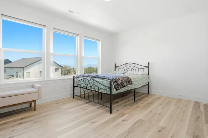 Bright interior room featuring a wall of three large windows, light wood-finish flooring, white walls, and white trim