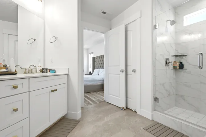 Modern bathroom featuring a glass-enclosed shower with a rainfall showerhead, integrated shelving, and white marble-look tile