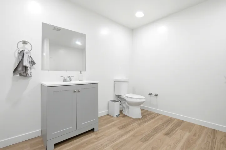 Powder room featuring a light gray vanity with a white countertop and a wall-mounted mirror