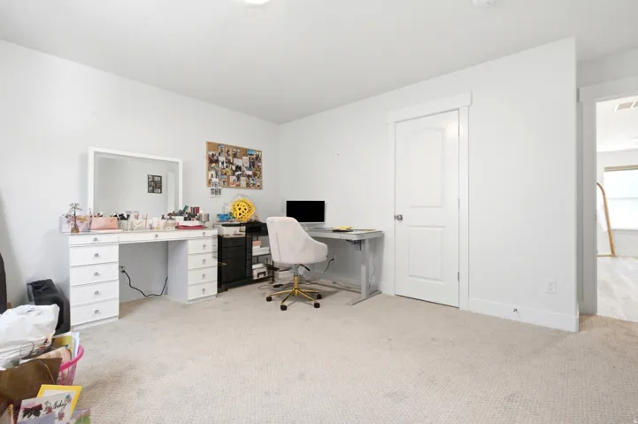 Carpeted room featuring a white interior door with a rounded panel design, white baseboards, and a doorway leading to an area with wood-finish flooring