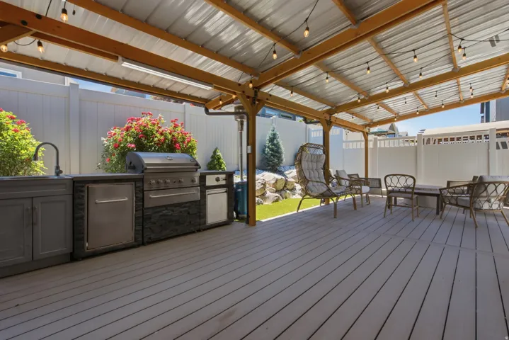 Covered patio featuring an outdoor kitchen with integrated grill, sink, and stainless steel appliances