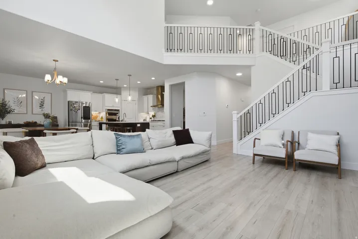 Two-story living area featuring light wood-finish flooring and a multi-level staircase with decorative metal balusters
