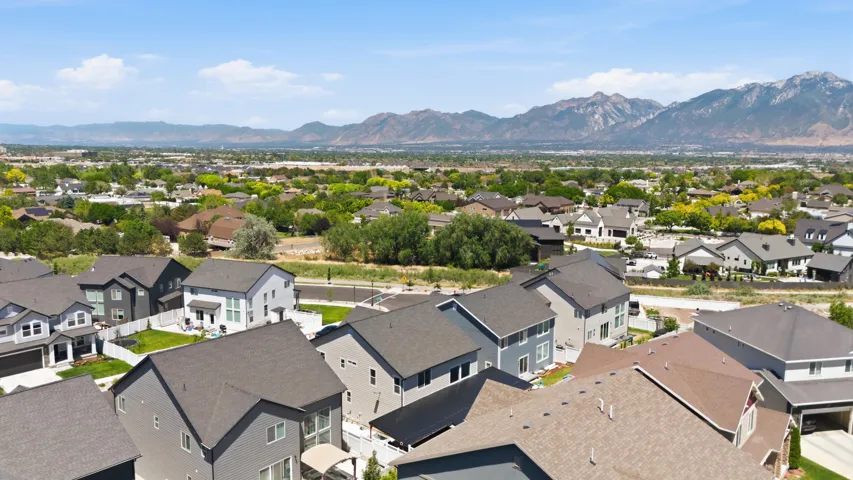 Expansive residential area featuring numerous modern homes with varying roof styles, including gable and hip designs, set against a backdrop of distant mountains