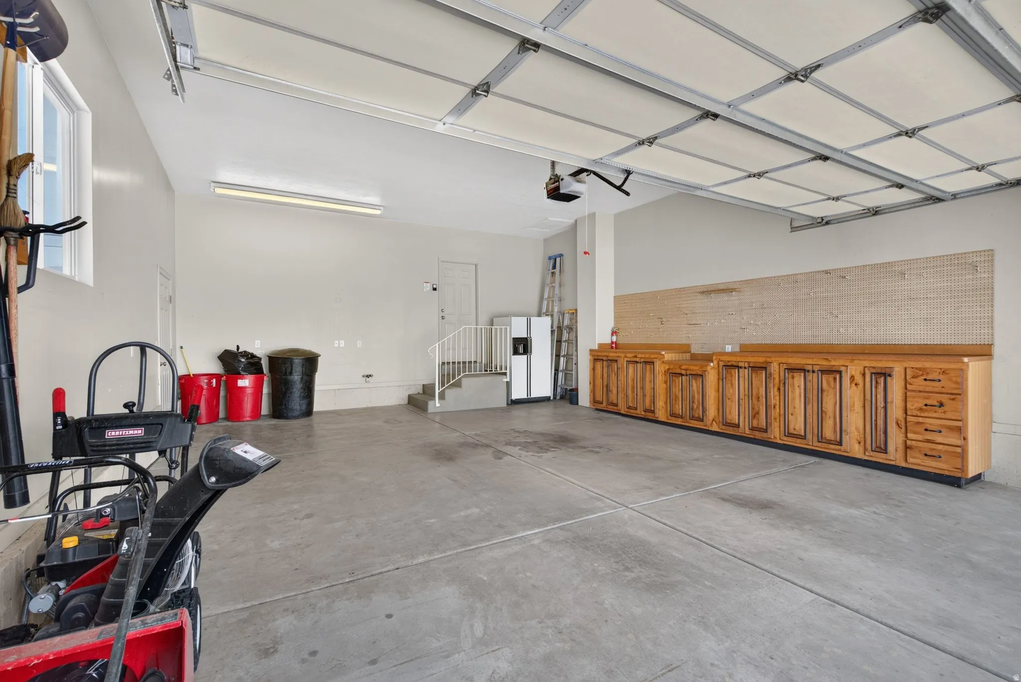 Spacious garage featuring concrete flooring and a built-in workbench with extensive cabinetry