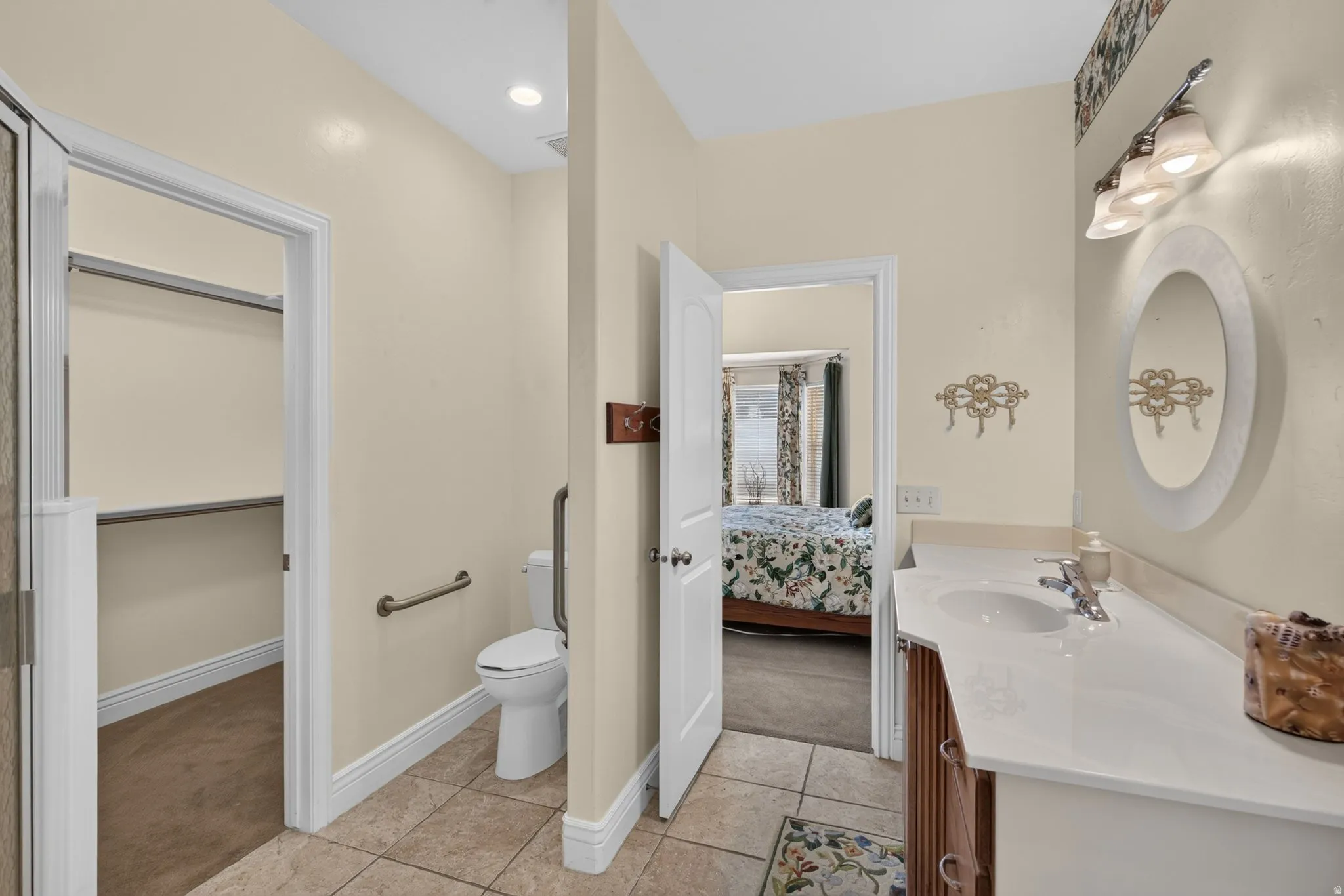 Bathroom featuring a vanity with an integrated sink, a large oval mirror, and overhead sconce lighting