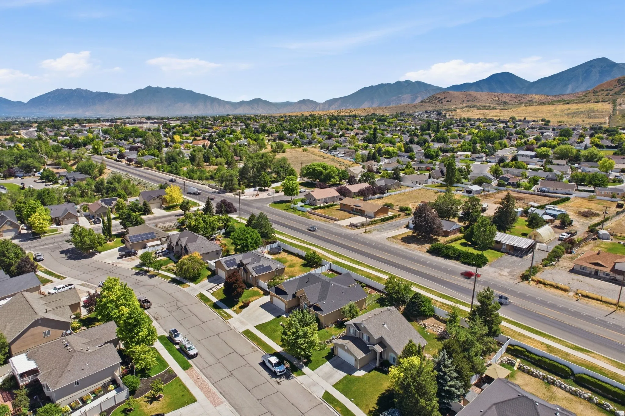 Residential neighborhood with established homes and mature trees, featuring paved streets and mountain scenery