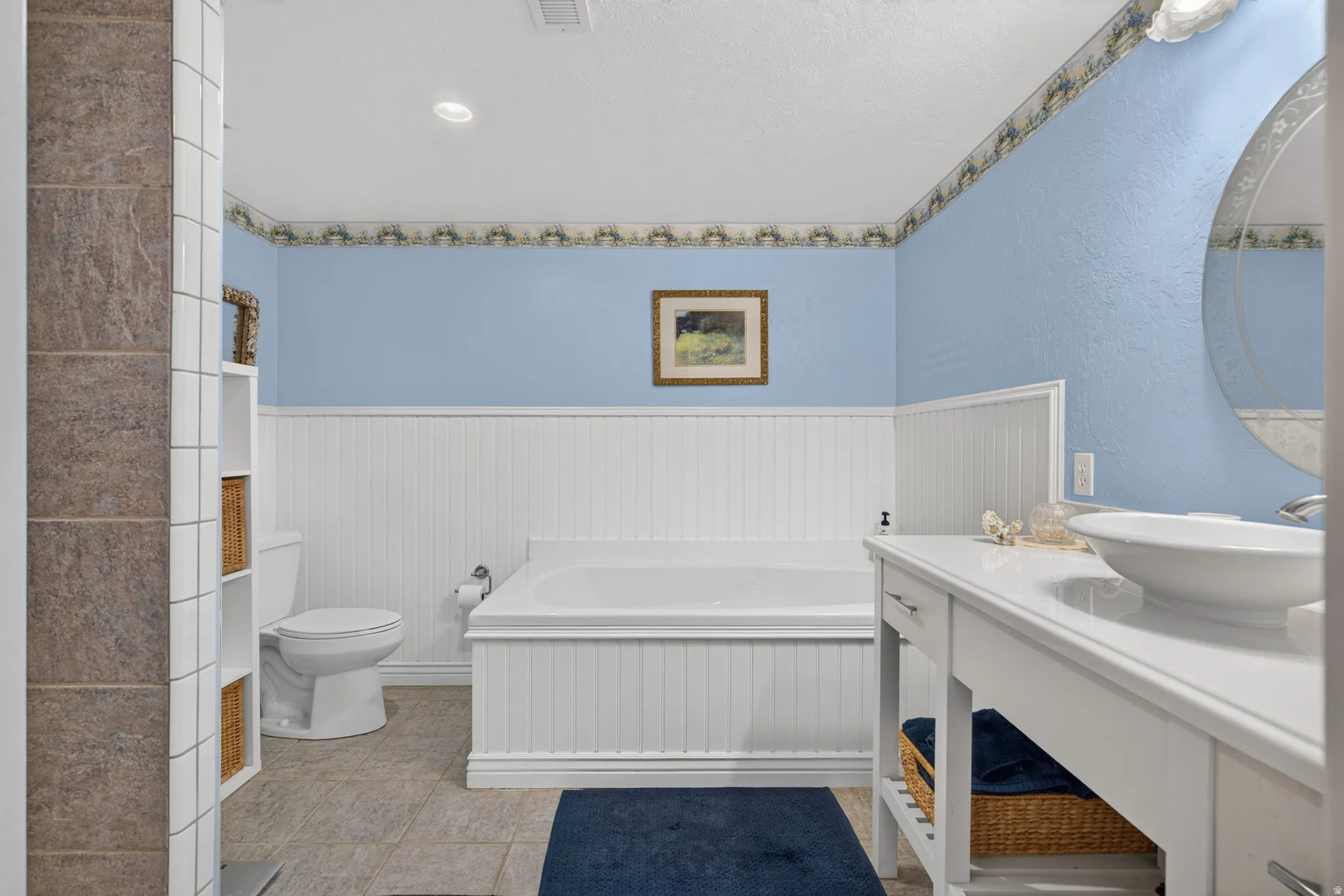 Bathroom featuring a built-in soaking tub, beadboard wainscoting, and a single vanity with a vessel sink
