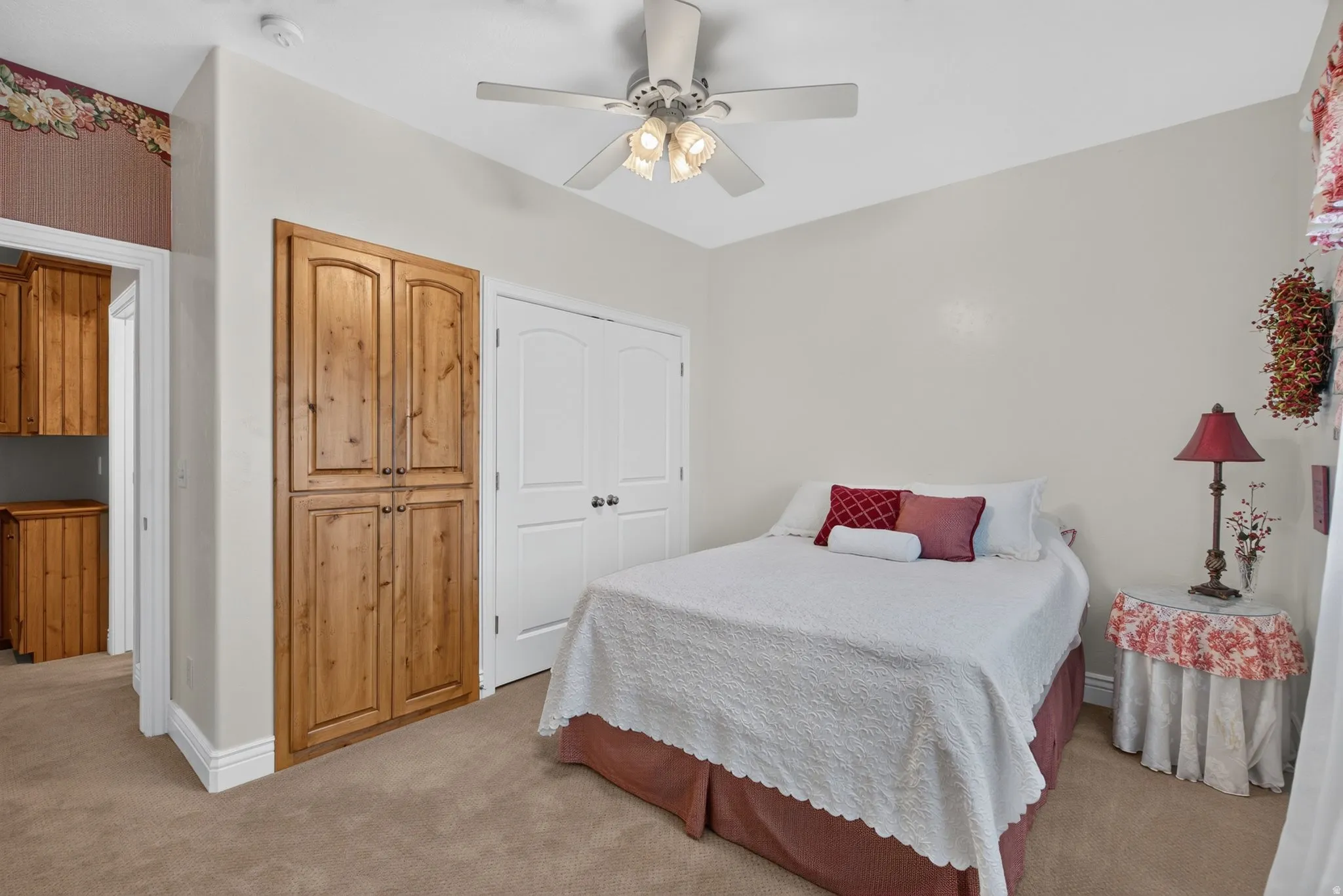 Carpeted room featuring a built-in wood-finish storage cabinet and a white bi-fold closet door