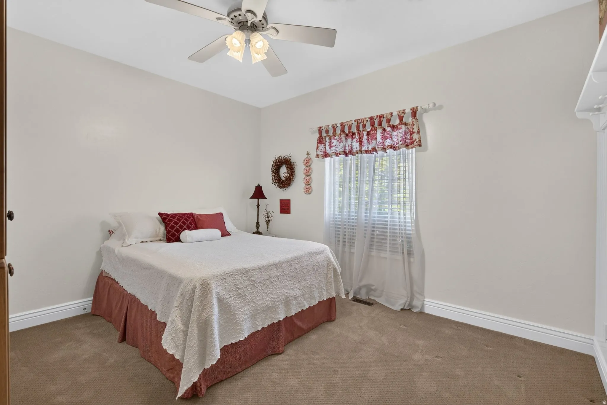Neutral-toned room with plush carpeting and a ceiling fan