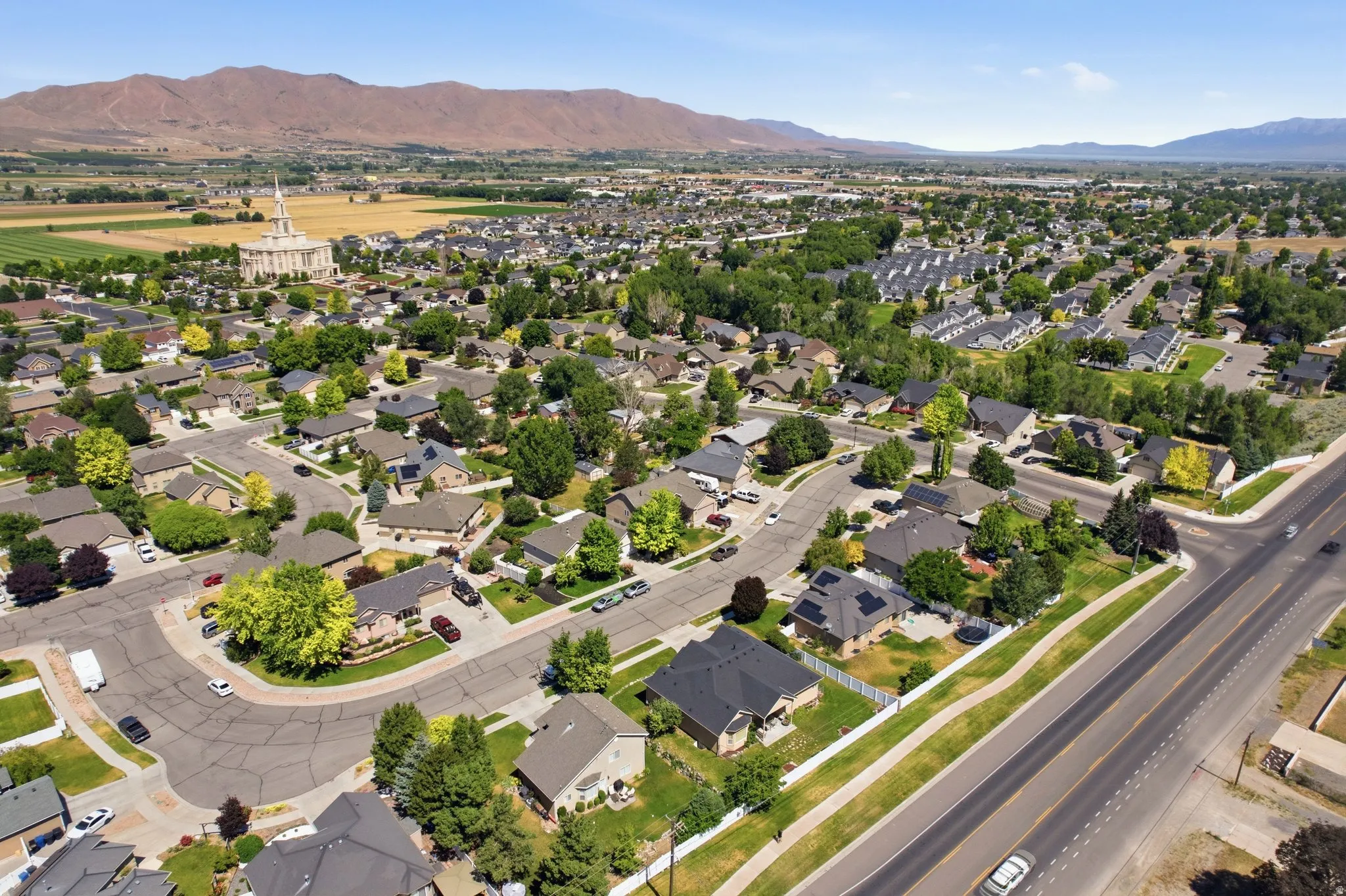 Expansive aerial showcasing a residential neighborhood with a distant mountain backdrop