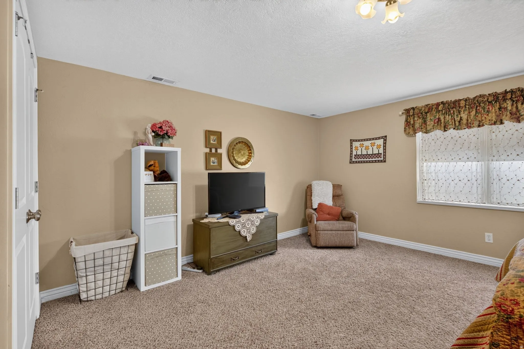 Carpeted room with a ceiling light fixture and a window with blinds
