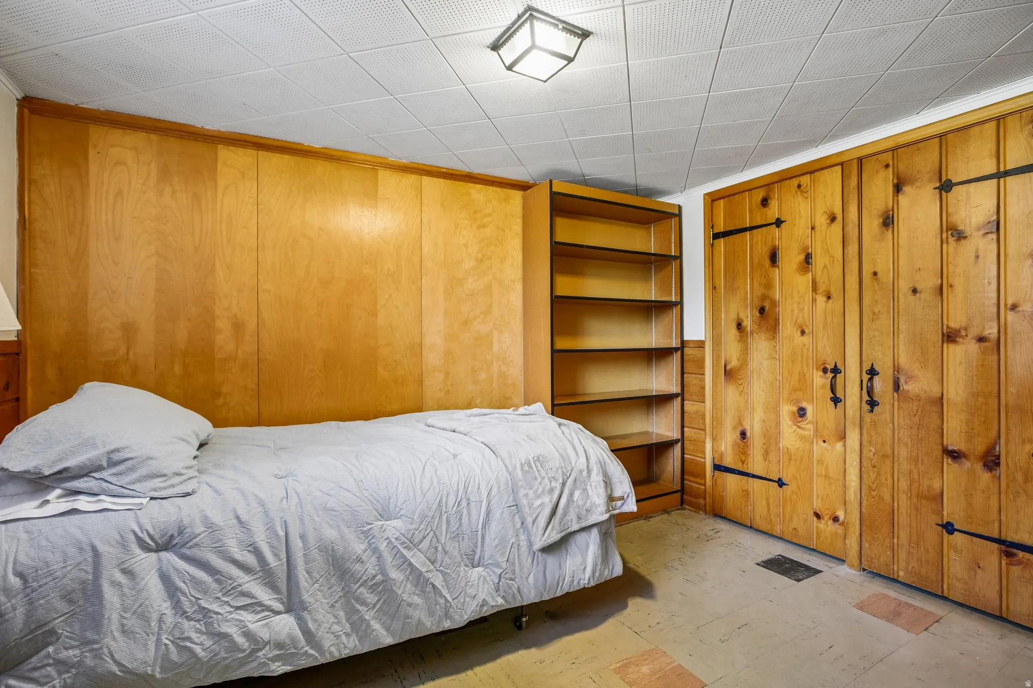 Wood-paneled room featuring a built-in shelving unit and a ceiling-mounted light fixture
