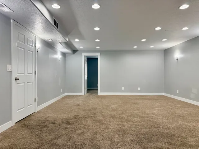 Spacious room with a neutral carpet, light gray wall paint, and white trim