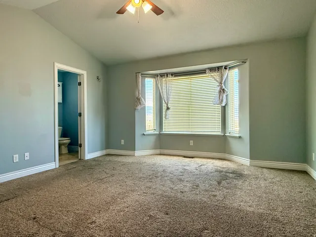 Carpeted room with a bay window featuring horizontal blinds