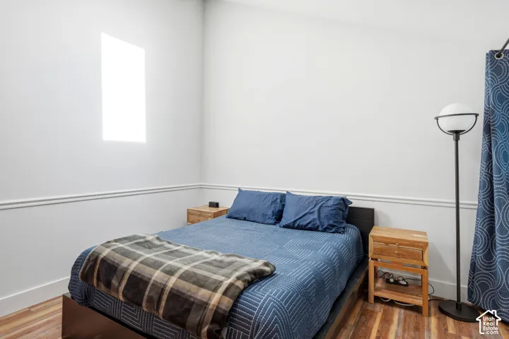 White walls with decorative chair rail molding, wood-finish flooring, and a single window