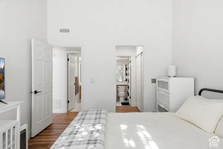 Vaulted ceiling bedroom featuring wood-finish flooring and bright white walls