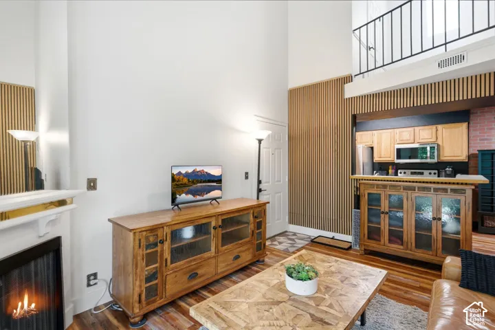 Vaulted ceilings with a loft overlook, wood-finish flooring, and a decorative fireplace