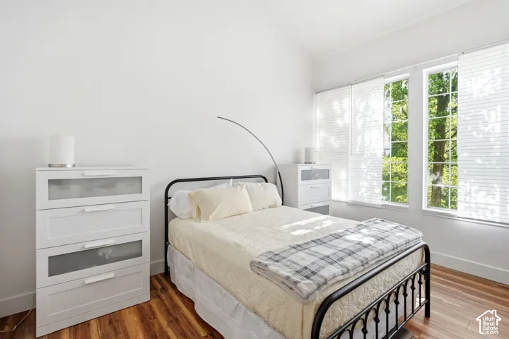 Bright room featuring wood-finish flooring, white walls, and a vaulted ceiling