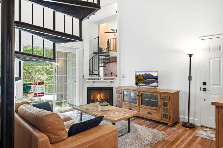 Living area featuring a fireplace with white mantel, a spiral staircase, and wood-finish flooring