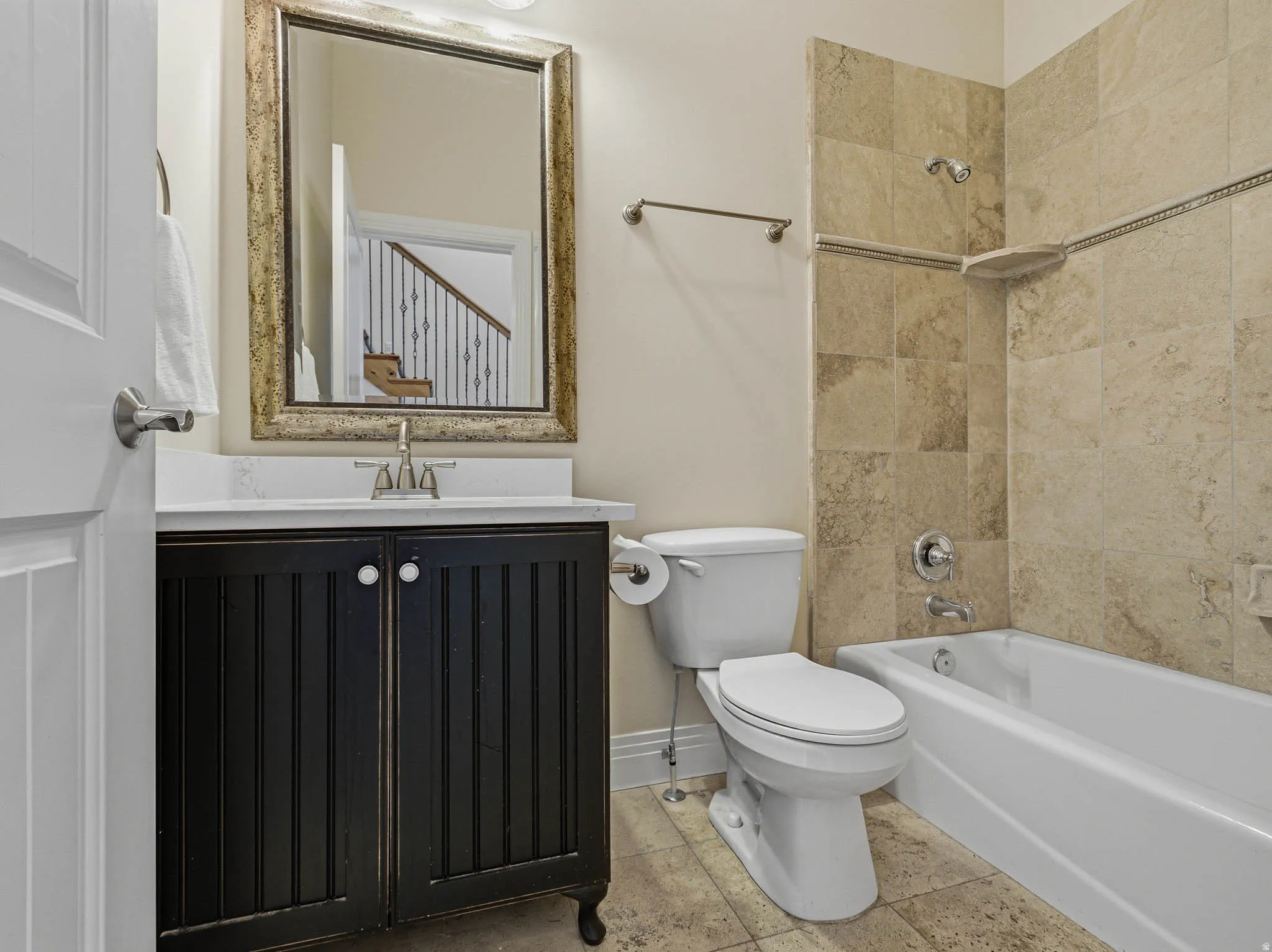 Bathroom featuring a dark wood-finish vanity with a white countertop and rectangular sink, a framed mirror, a standard toilet, and a white bathtub with tile surround
