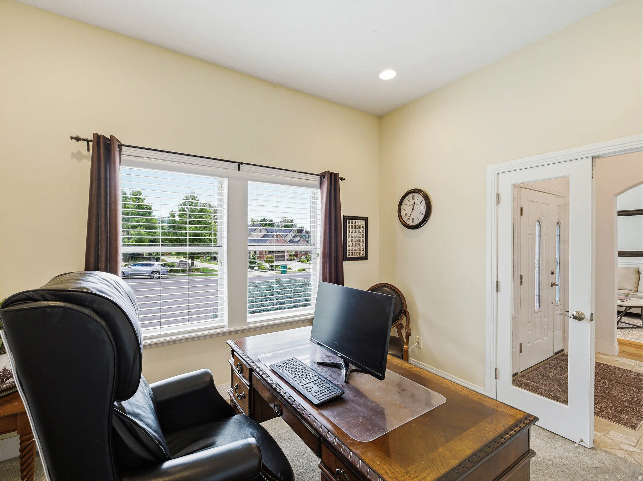 Bright room featuring two large windows with blinds, a tray ceiling, recessed lighting, and a glass-paneled door