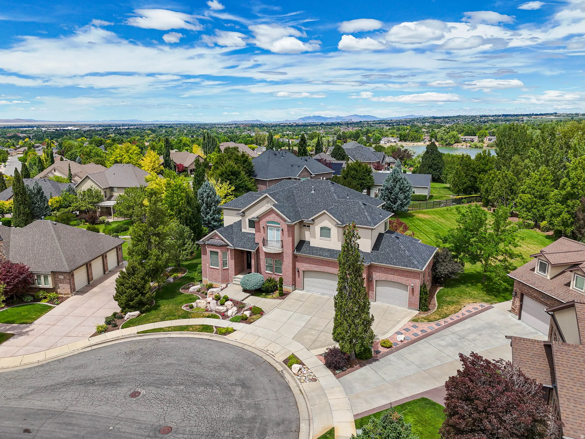 Brick and stucco residence featuring a prominent bay window, attached two-car garage, and a semicircular driveway