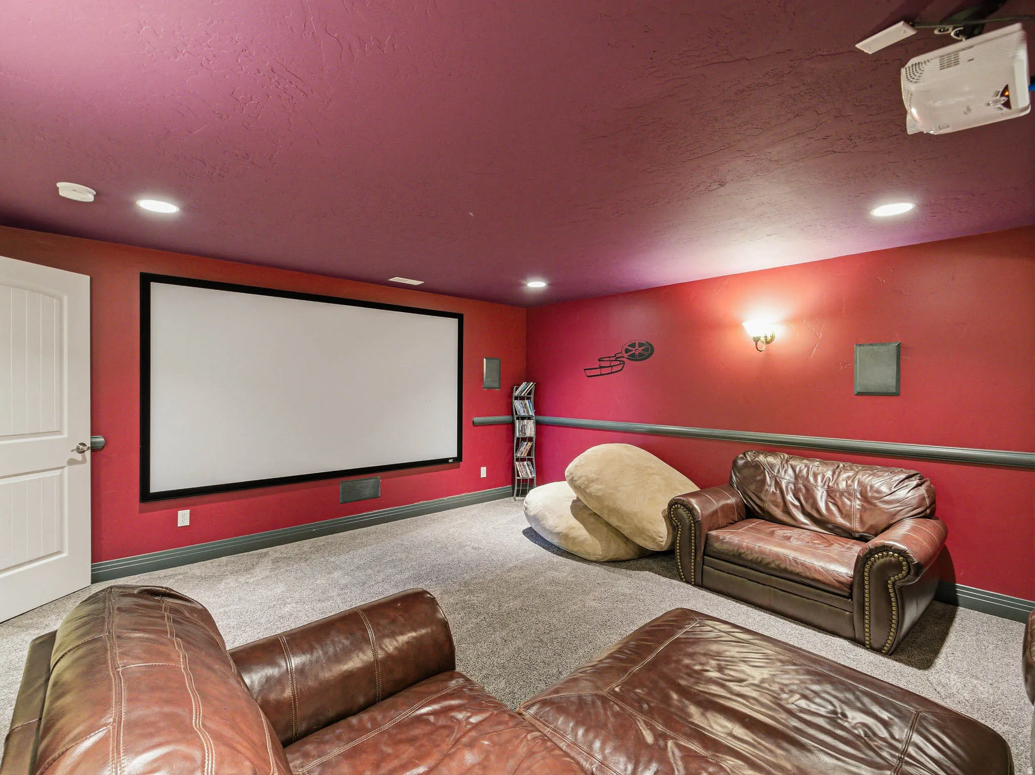 Dedicated media room featuring a large projection screen, projector, and built-in speakers