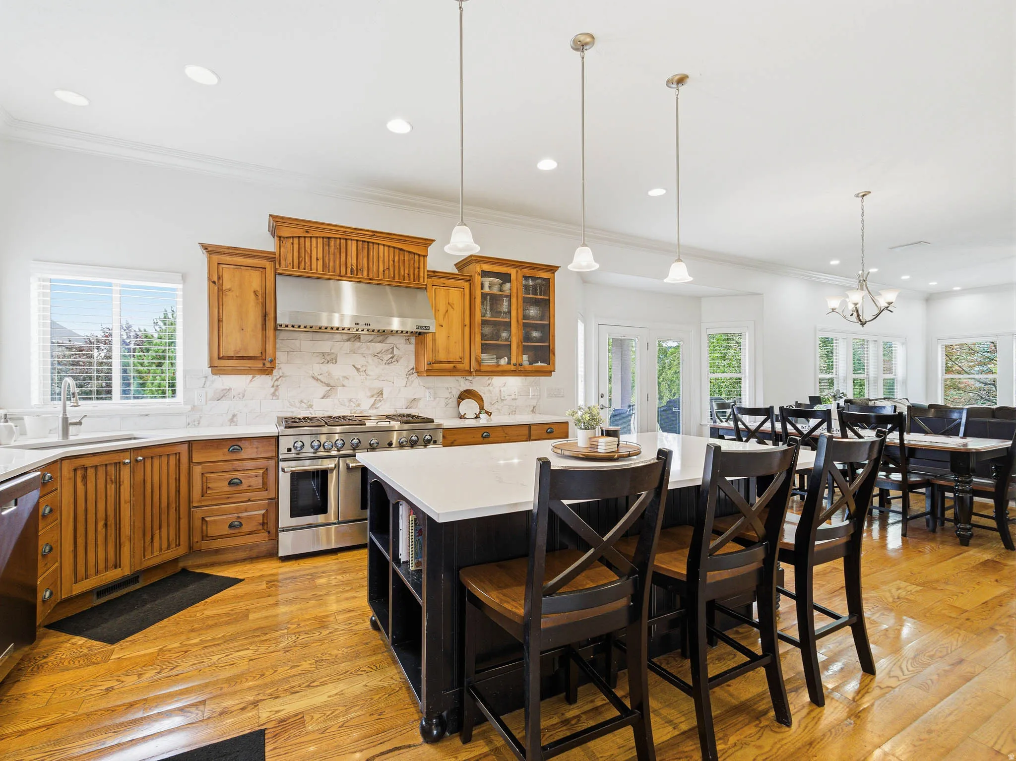 Spacious kitchen featuring warm wood cabinetry, stainless steel range with matching hood, and light-toned countertops
