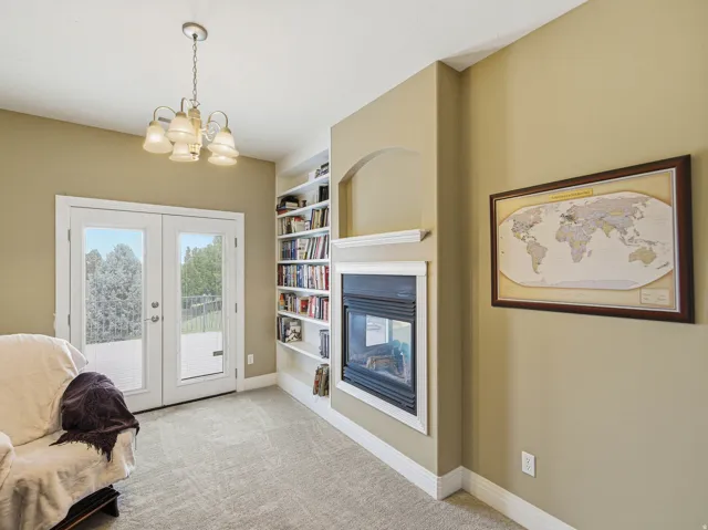 Room featuring built-in shelving, a fireplace with mantel, and white French doors