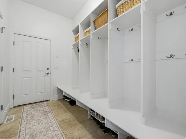 Built-in cubbies and shelving featuring multiple coat hooks and shoe storage