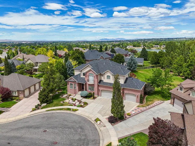 Brick and stucco residence featuring a prominent bay window, attached two-car garage, and a semicircular driveway