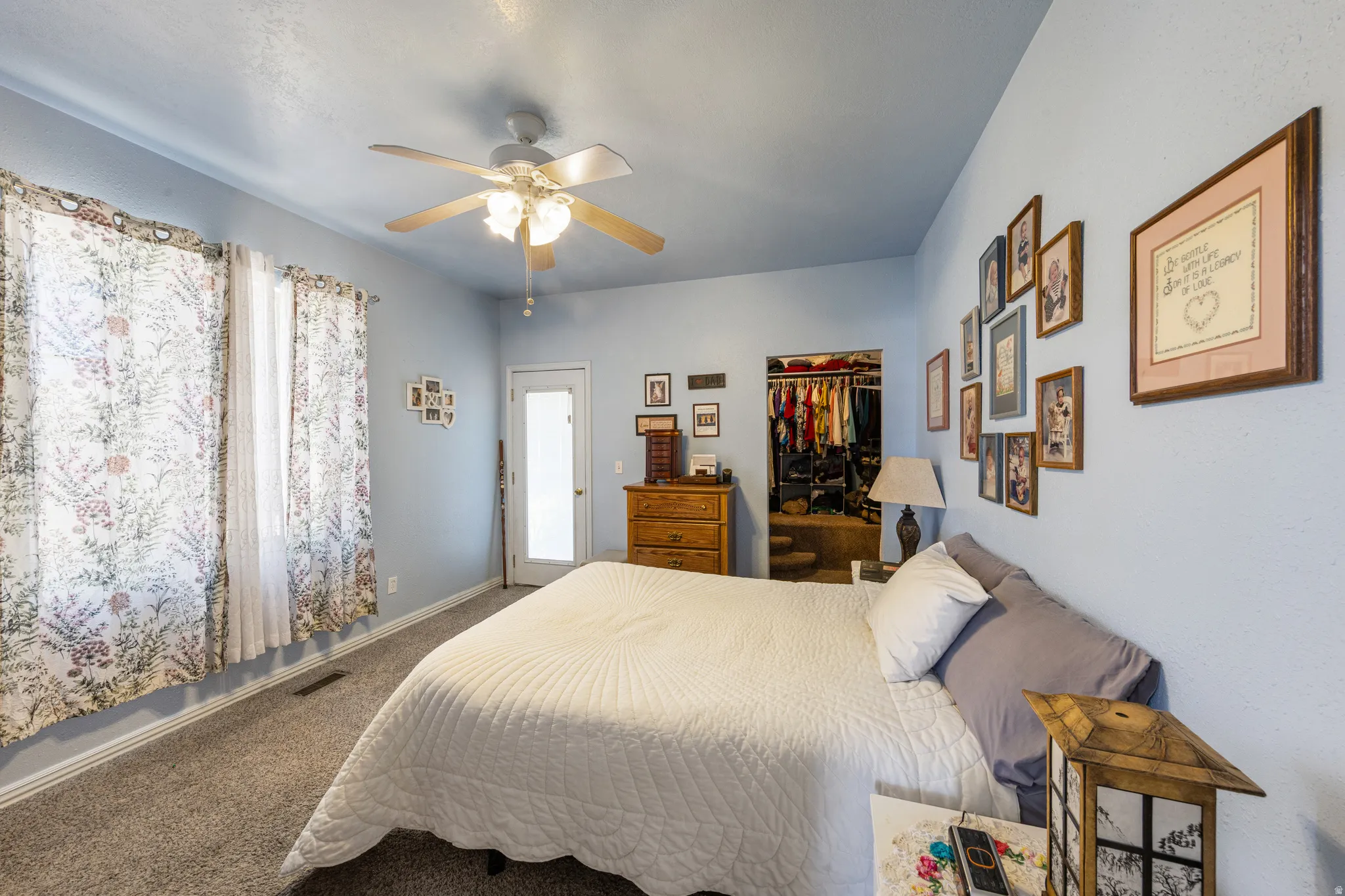 Bedroom featuring light blue walls, gray carpet, and a ceiling fan with light fixture