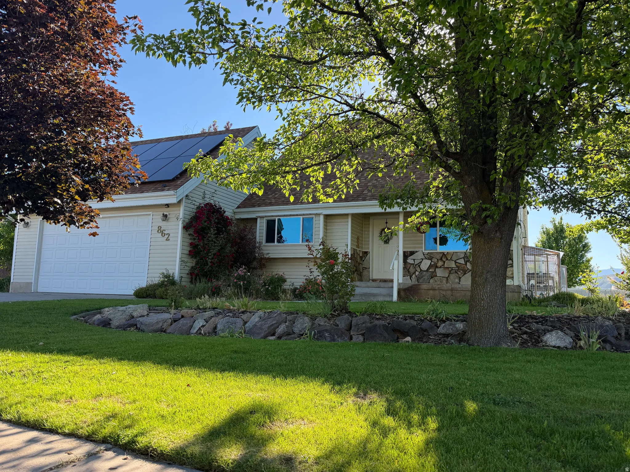 Exterior showcasing a stone facade, a covered front porch, and an attached garage with a white door