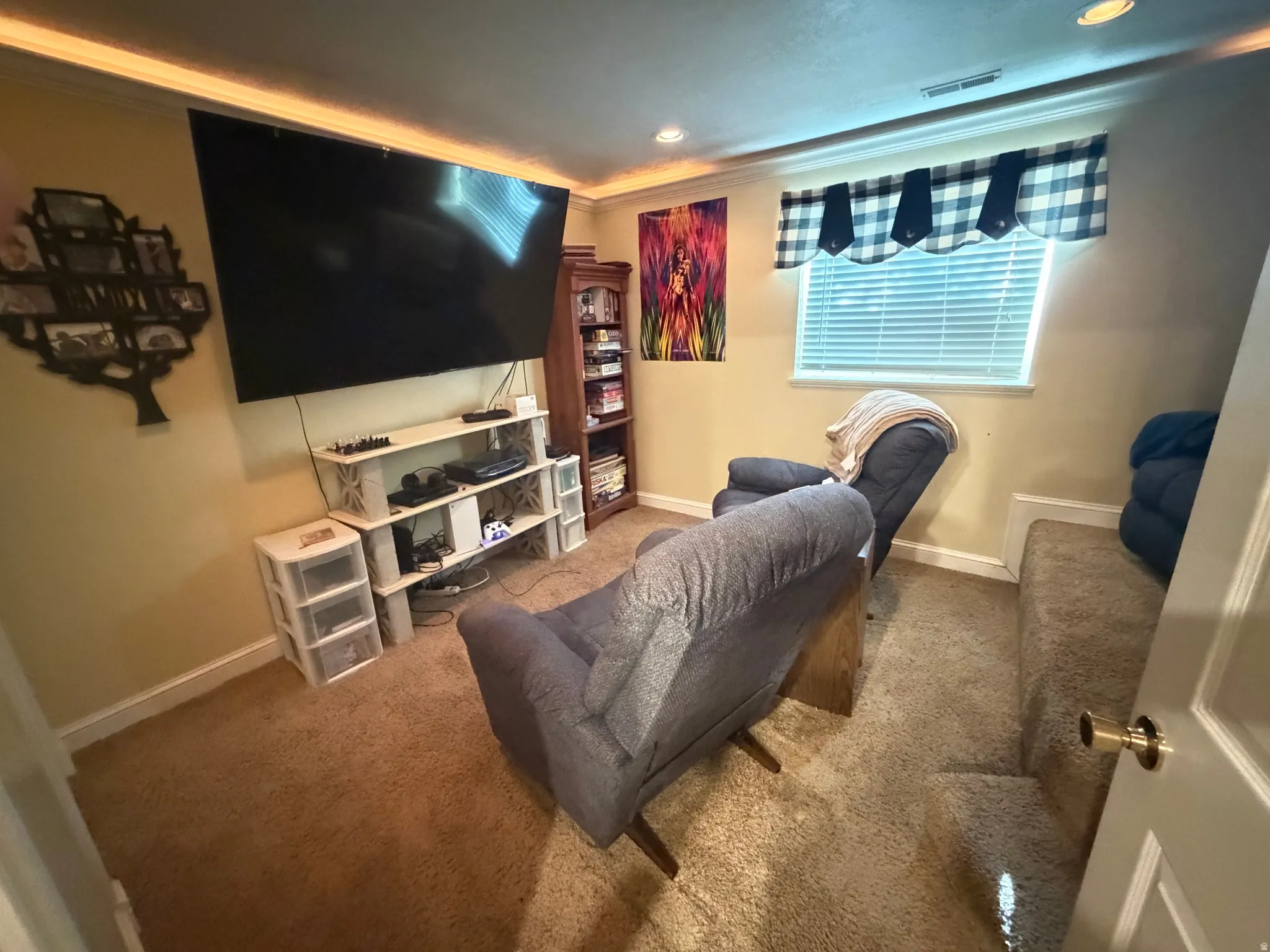 Carpeted room featuring a wall-mounted television, built-in shelving, a window with blinds, and recessed lighting