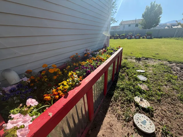 Vibrant flower bed with a red-framed planter, featuring diverse colorful blooms