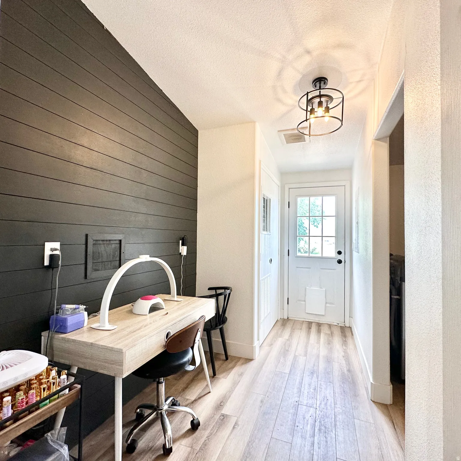 Hallway with wood-finish flooring, a dark accent wall, and a white paneled door with glass inserts