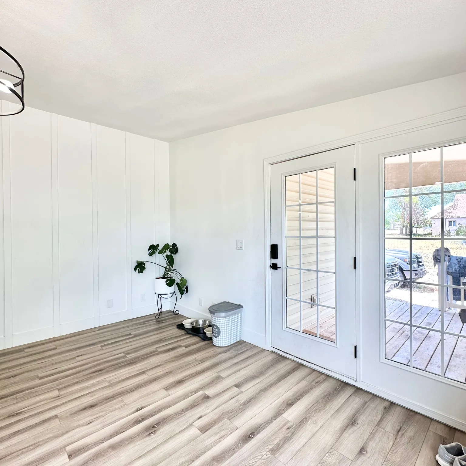 Spacious interior featuring wood-finish flooring, white shiplap accent wall, and a modern ceiling light fixture