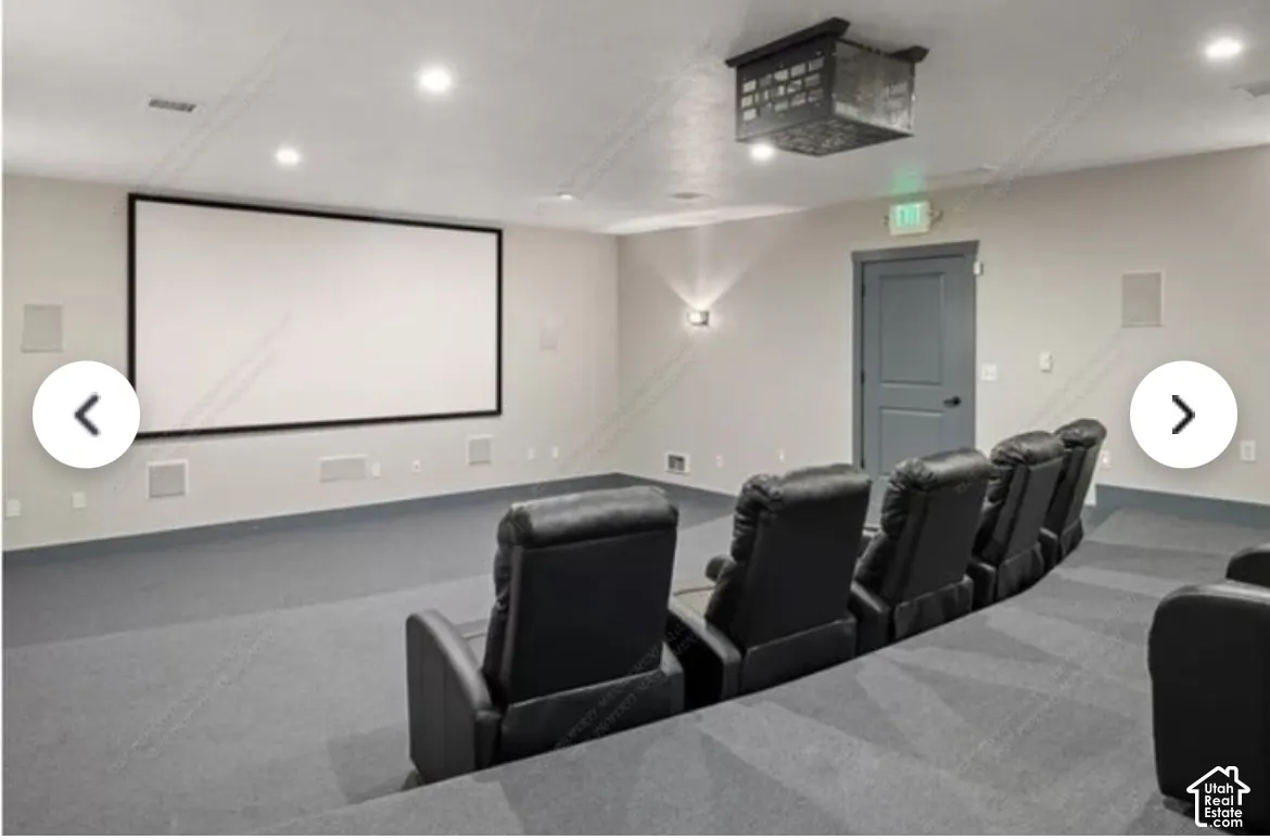 Dedicated home theater featuring a large projection screen, integrated ceiling speakers, recessed lighting, and graded stadium seating