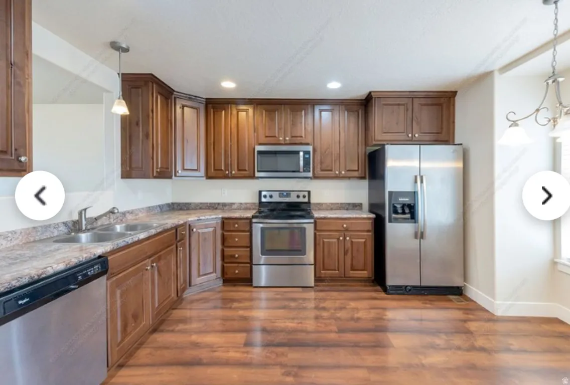 Kitchen featuring wood-finish flooring, dark wood cabinetry, and stainless steel appliances