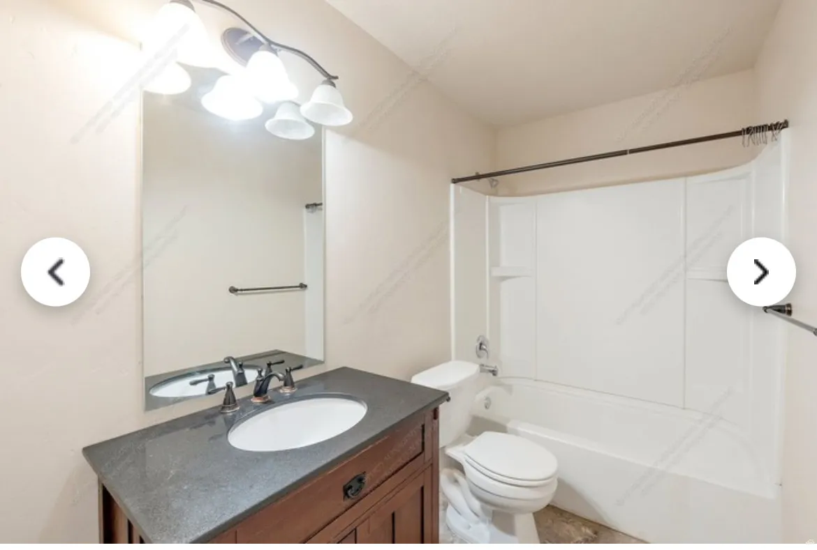 Bathroom featuring a vanity with a dark countertop, white oval sink, and bronze-finish faucet