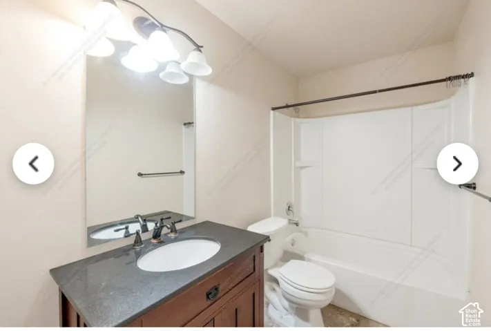 Bathroom featuring a vanity with a dark countertop, white oval sink, and bronze-finish faucet