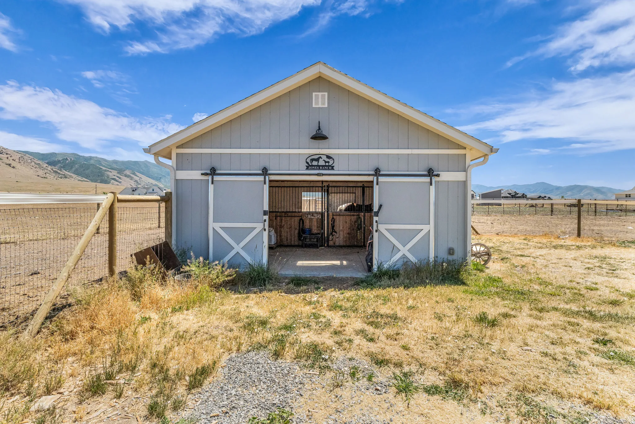 Light gray barn structure featuring a white gable roof and dark trim two stall barn could be used for foaling.
