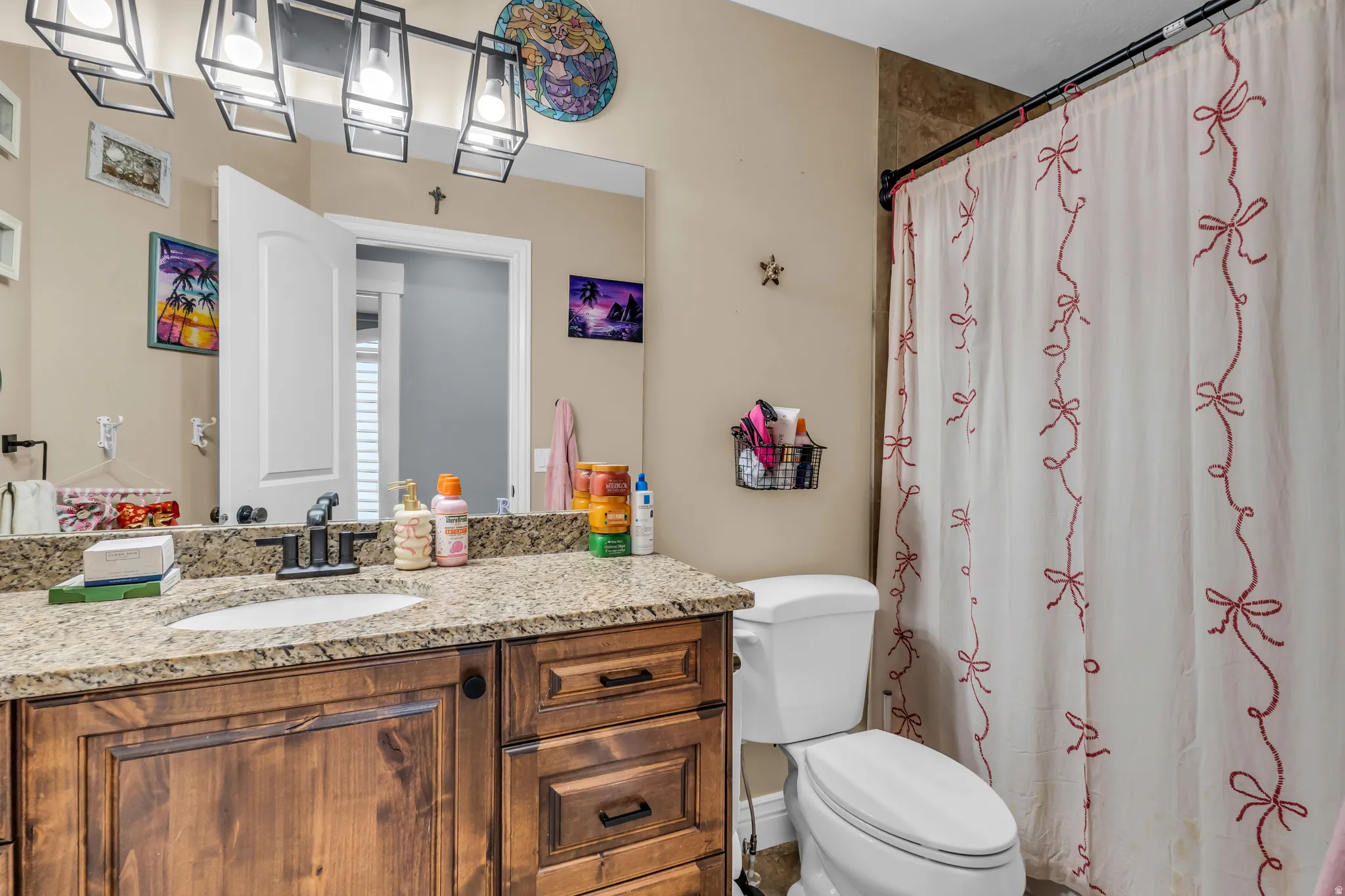 Bathroom featuring a wood-finish vanity with an integrated sink and a granite countertop