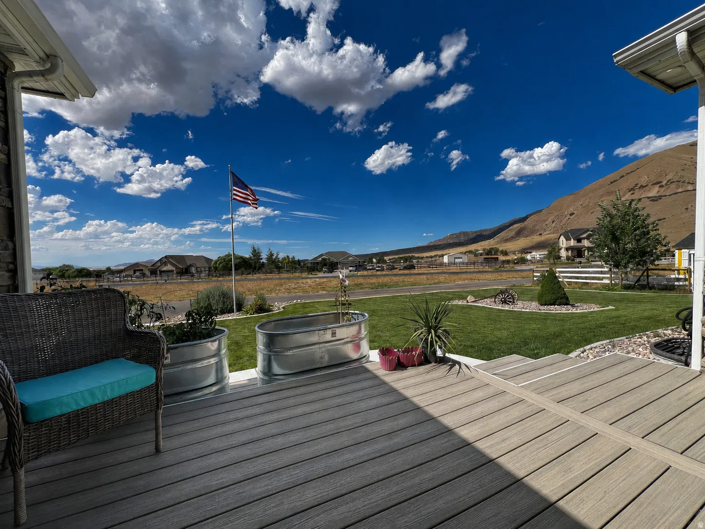 Spacious outdoor deck featuring composite decking, a manicured lawn area, and mountain scenery