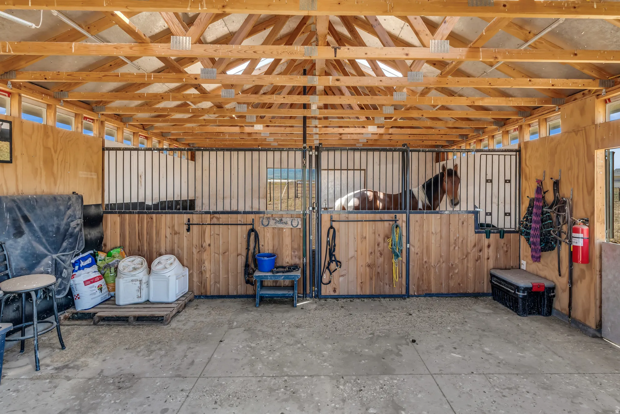 Open-air barn structure featuring exposed wood framing and a concrete floor
